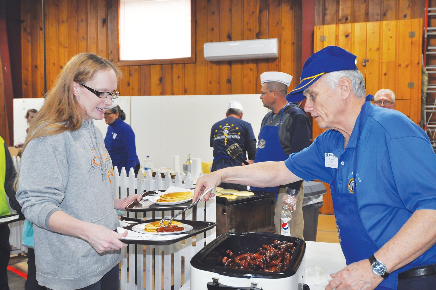 Dave Long serves sausages to Regina Lowrey at the Kiwanis Club Pancake Day at the Montgomery County 4-H Fairgrounds in 2019.  The club has partnered with Crawfordsville